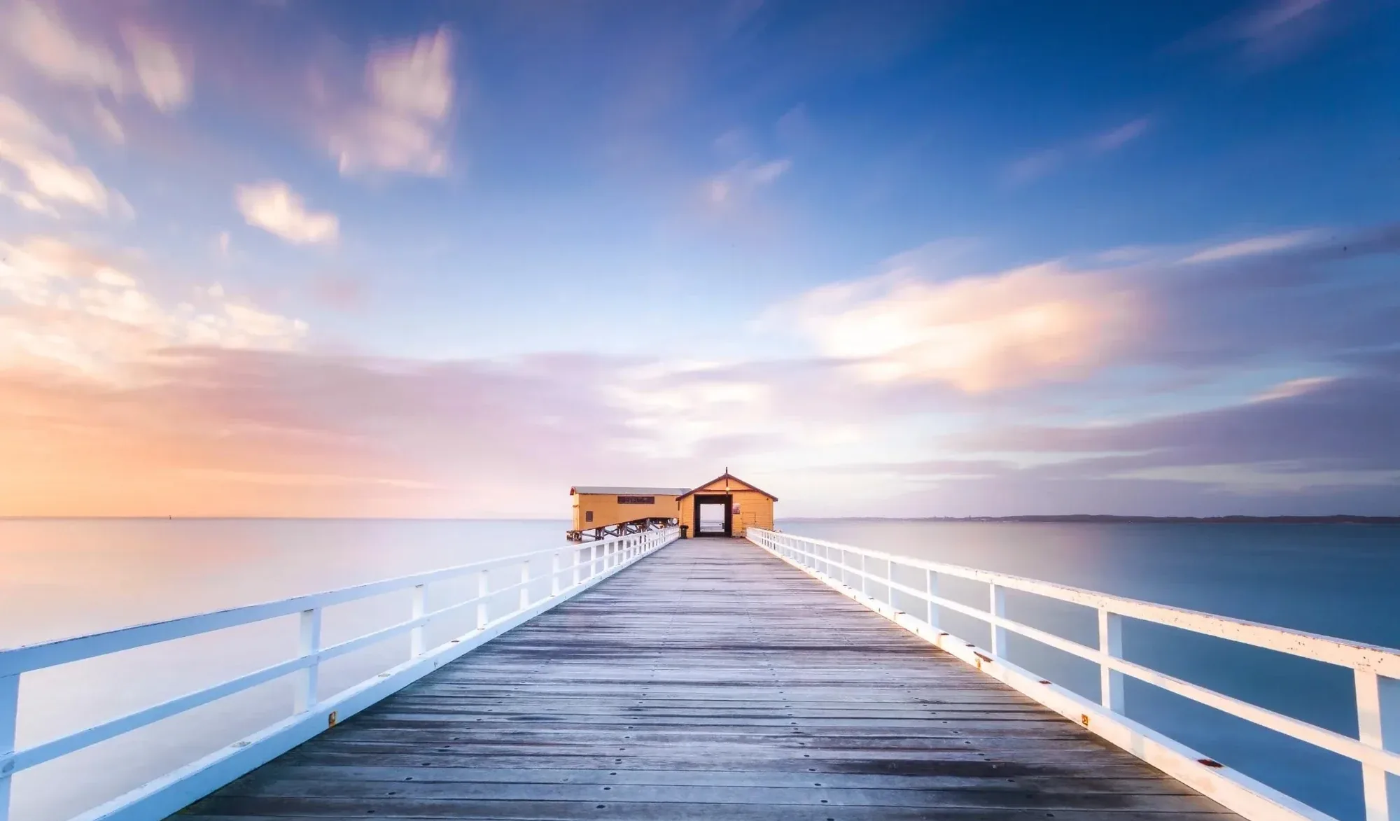 Wooden jetty stretching into calm water at sunrise on the Central Coast
